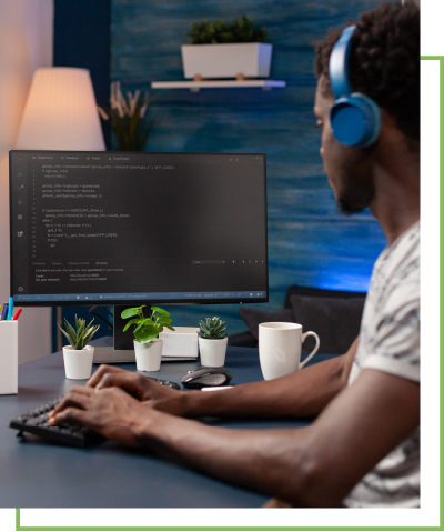 A man wearing headphones works on a desktop computer