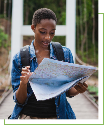 A woman reading a map on a bridge in a forest